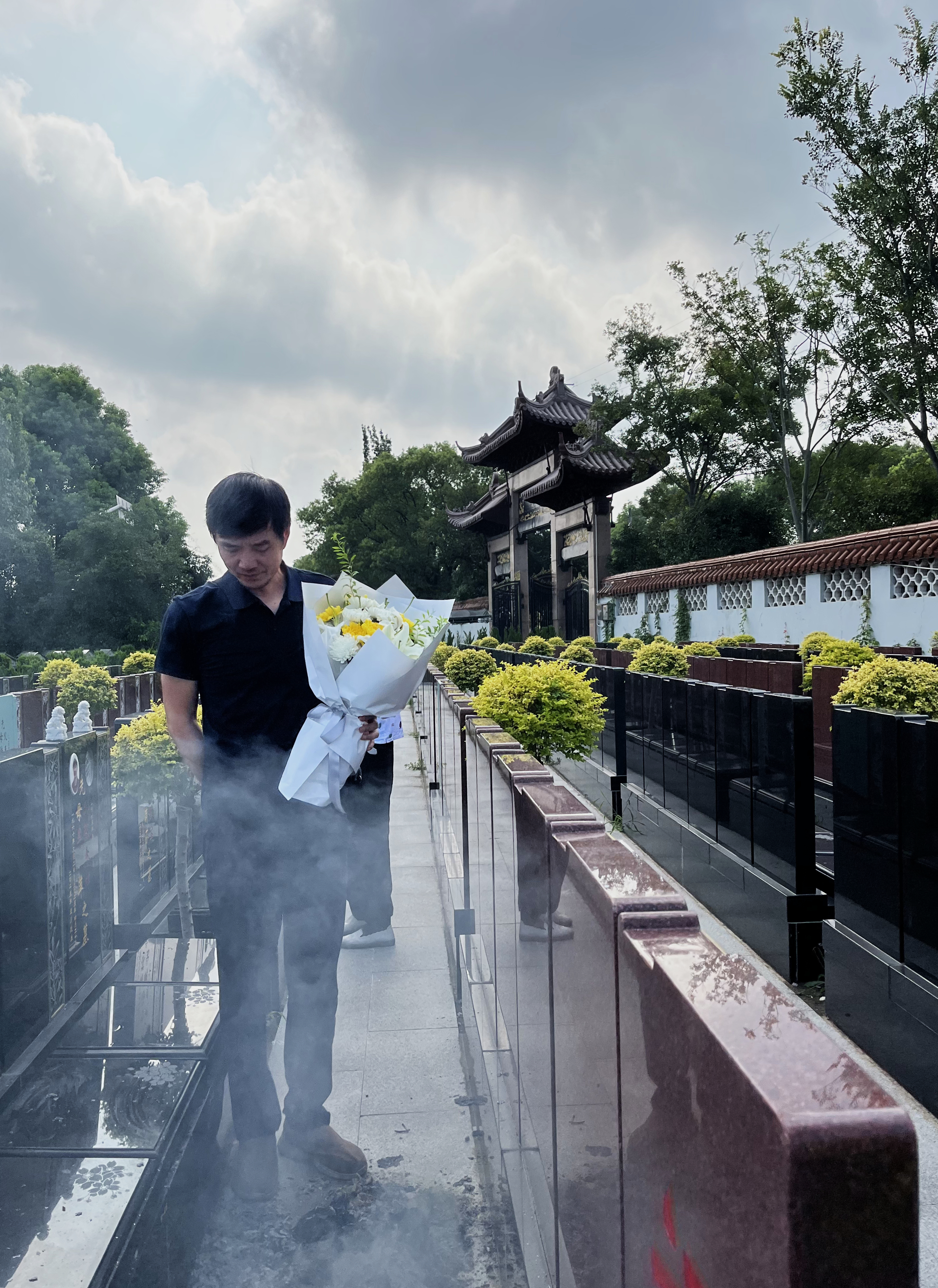 Deep Mourning — figure with flowers walking through incense smoke at a Chinese cemetery.