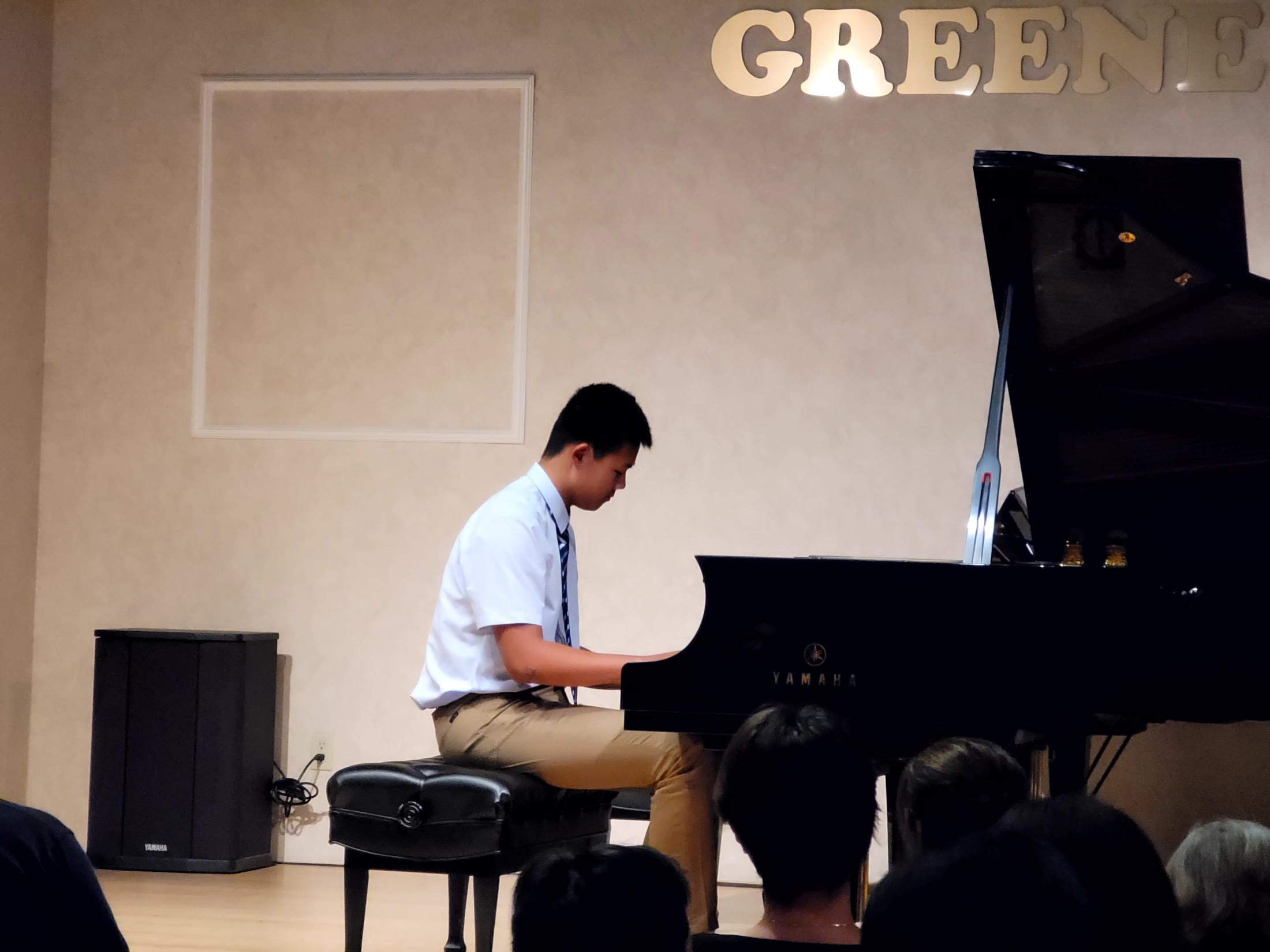 Keshu playing a grand piano at a recital.