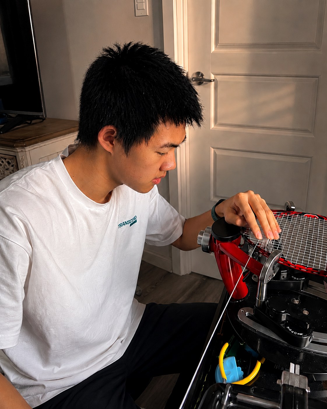Keshu stringing a badminton racket on the machine at home.